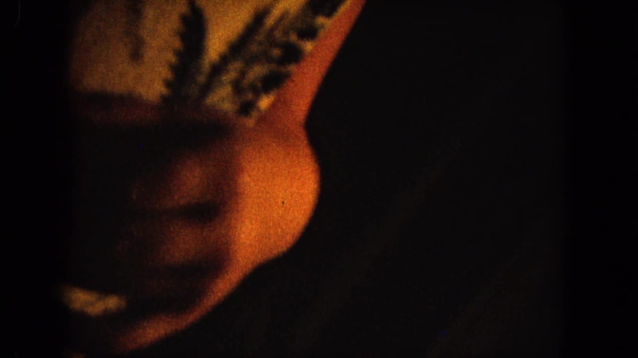 A hand and light patterned sleeve appear against a mostly dark background.