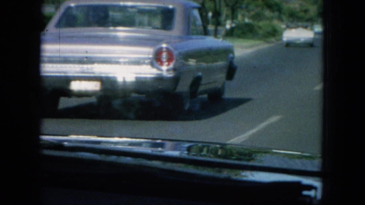 Silver sedan ahead on a paved road with dashboard and windshield visible.