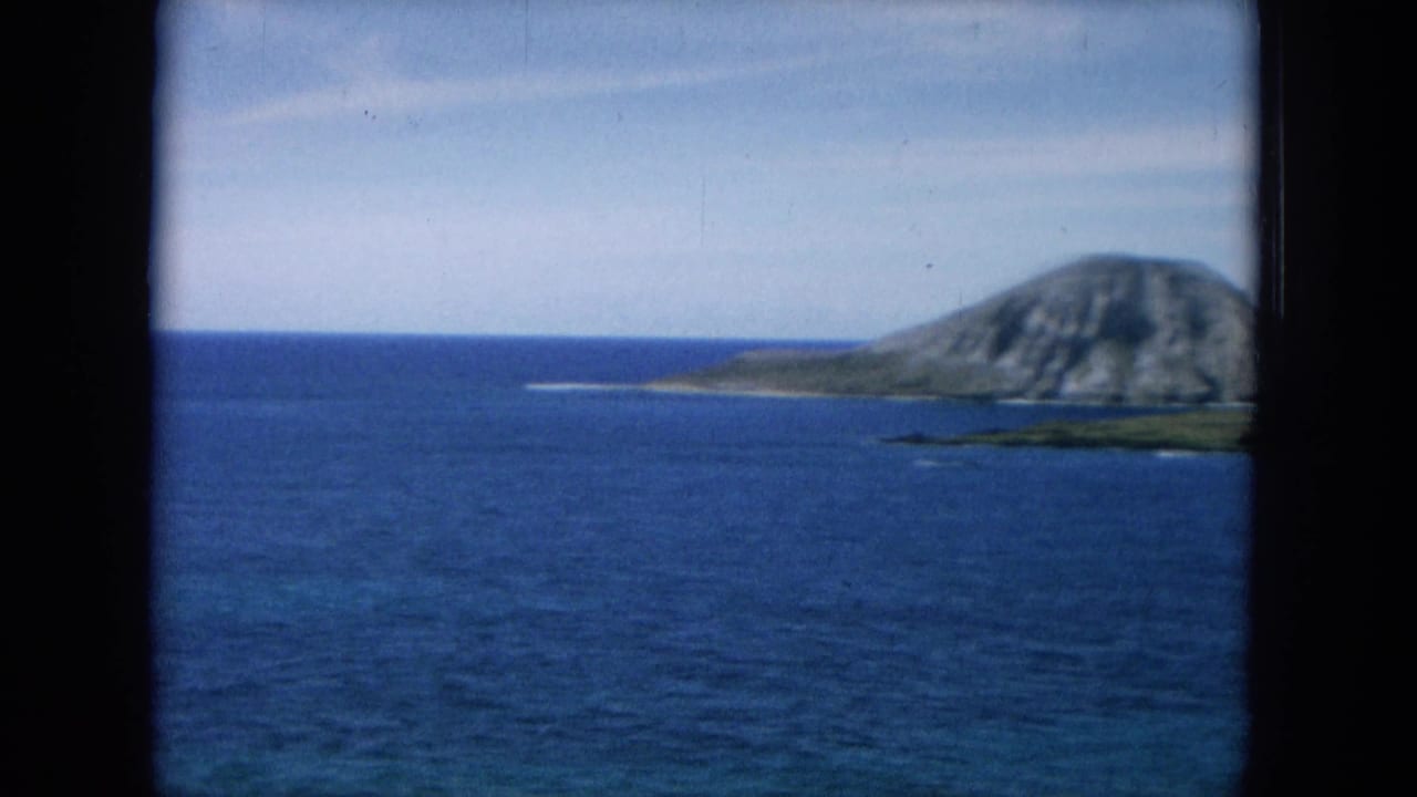 Blue ocean with a rocky volcanic landform seen through a dark window border.
