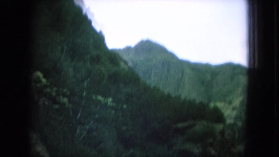 Soft 8mm frame of green valley slopes and mountain peaks from a moving car in Oahu, Hawaii.