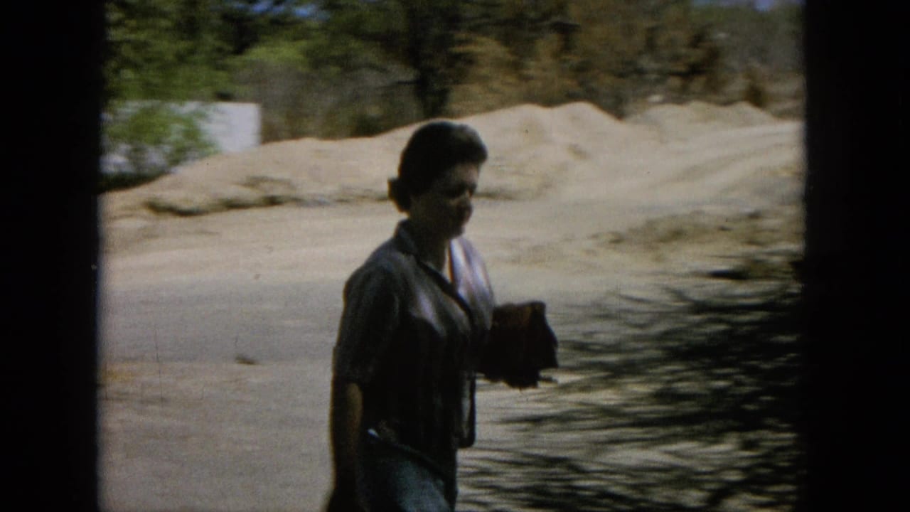 Woman walking beside water and pale rock while carrying a purse.