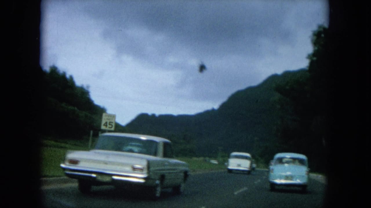 A light-colored sedan passes near a 45 mph sign on a mountain road.