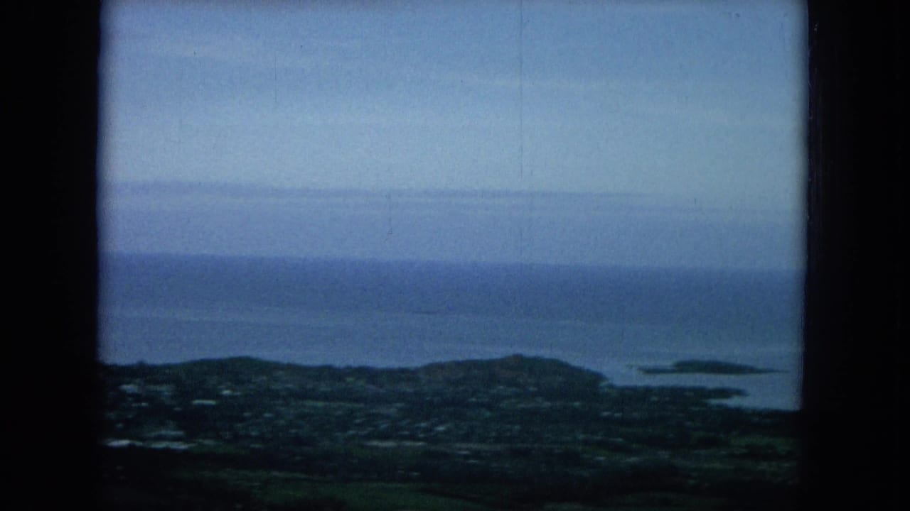 Wide ocean horizon above a coastal town and small islands seen from an elevated viewpoint.
