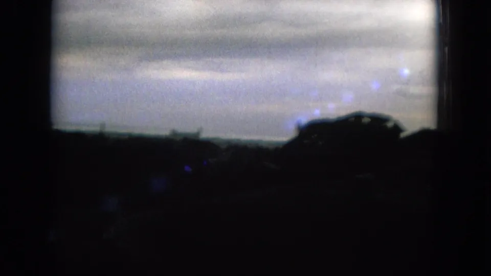 Distant Oahi, Hawaii skyline under overcast light, with a dark vehicle-like silhouette crossing the right foreground in the 8mm frame.