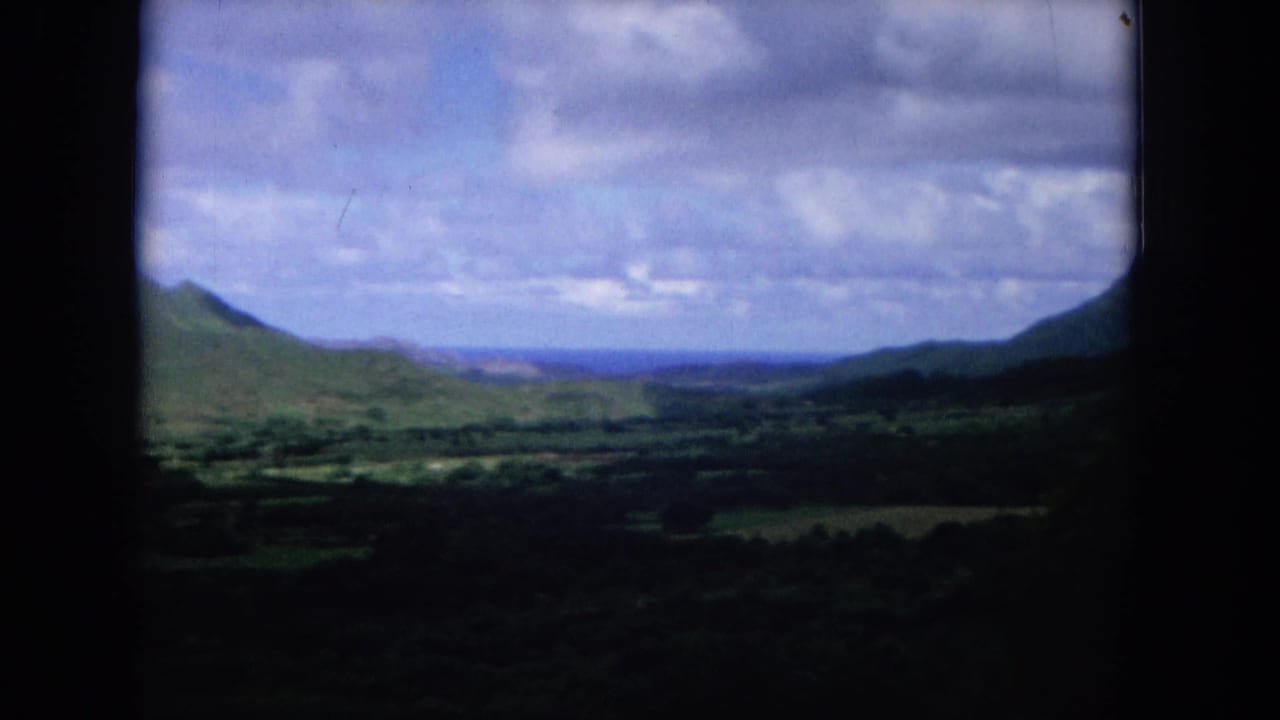 Distant green valley and mountain slopes beneath a cloudy sky.