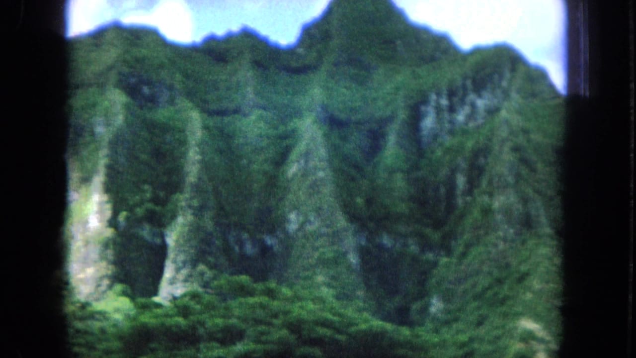 1964 Hawaii travel footage appears to show steep, vegetation-covered mountains framed by dark 8mm borders.