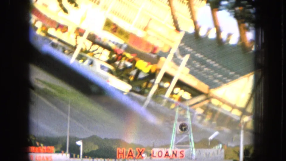 Tilted 8mm frame of a roadside commercial sign area in Hawaii with HAX LOANS lettering visible.