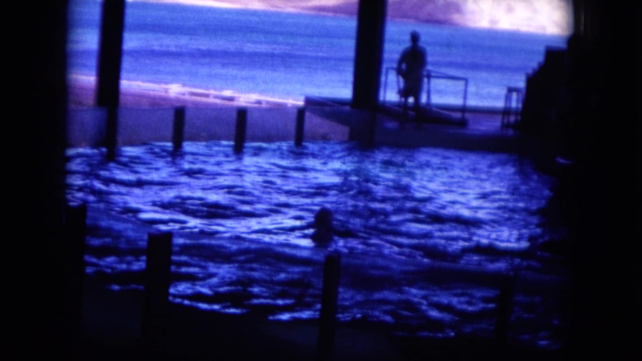 Dark observation view of blue water with a silhouetted person on a small platform.