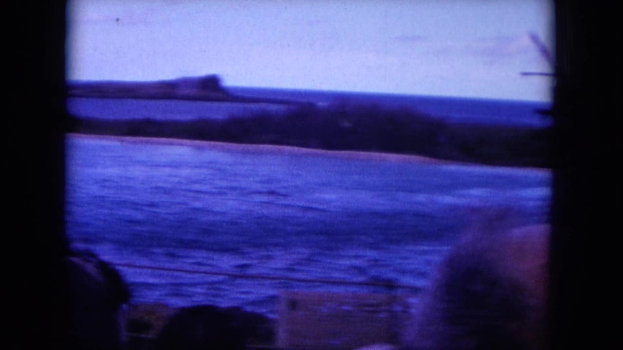 Blue ocean and distant shoreline seen through dark film frame edges.