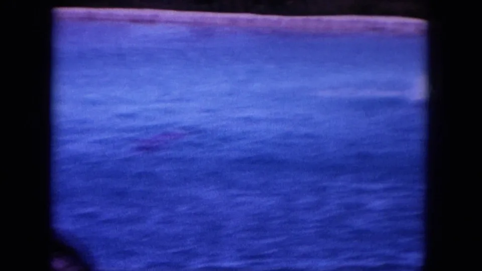 1964 Oahi, Hawaii 8mm frame holding on blue coastal water and a bright strip of shoreline.