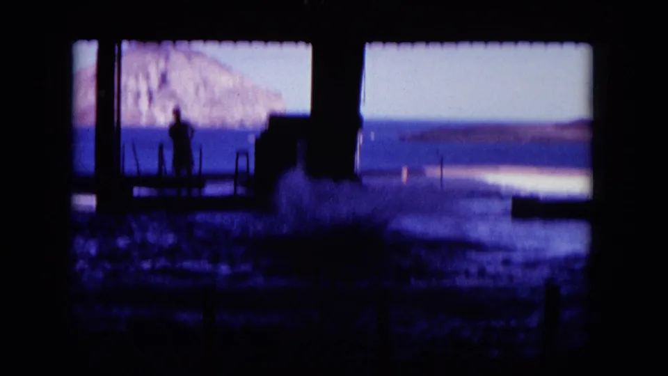 1964 8mm Hawaii frame showing water splashing after the dolphin jump near a silhouetted dockside figure.