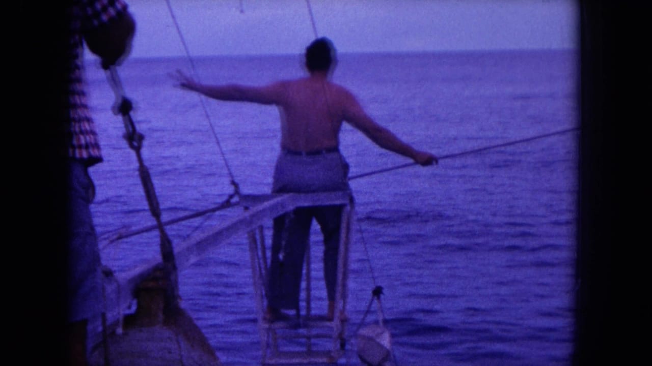 Man on a boat platform extends a long pole over open water.