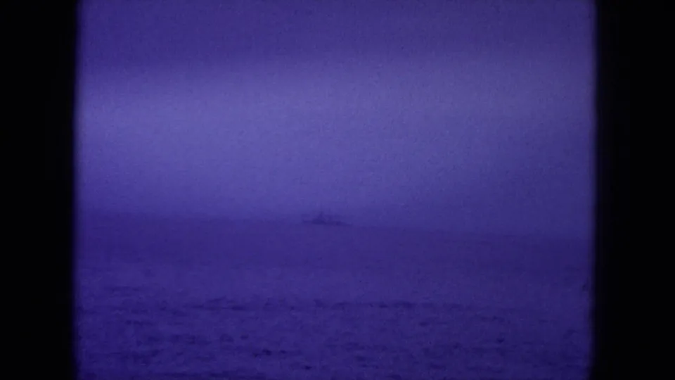 Purple-toned 8mm view of open water near Hawaii, with a faint distant ship along the horizon.