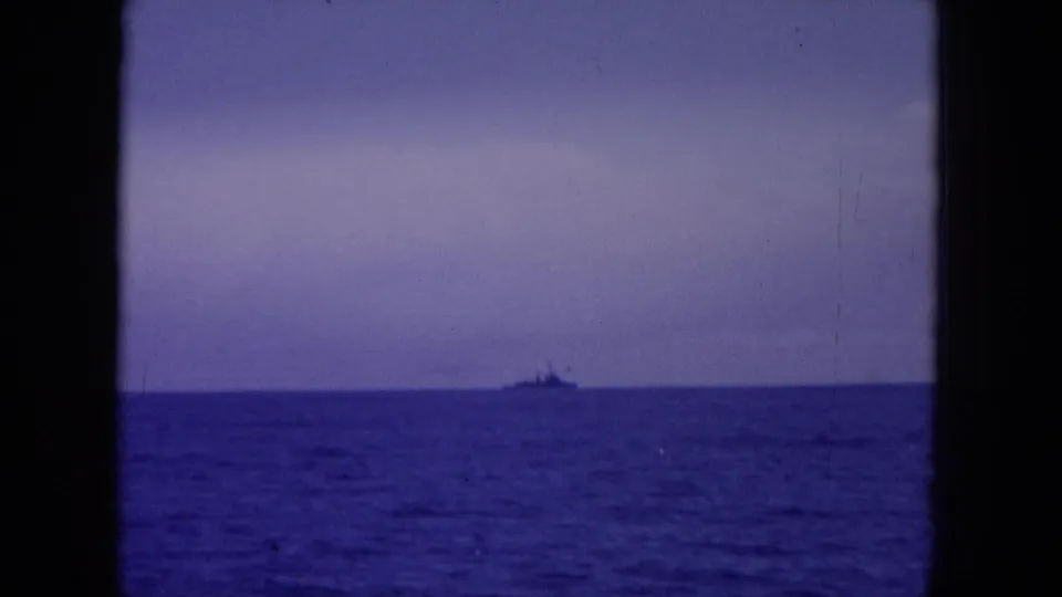 1964 Hawaii-area 8mm view of a distant ship crossing the horizon, with blue water below and a dark vertical window divider.
