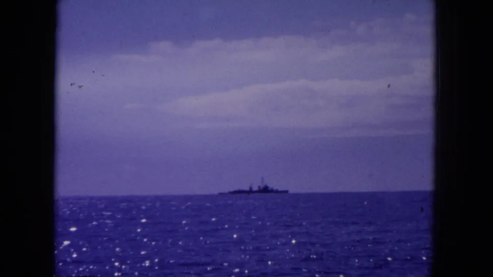 1964 Hawaii 8mm frame showing a distant ship-like vessel on the horizon over open water with dark film borders.