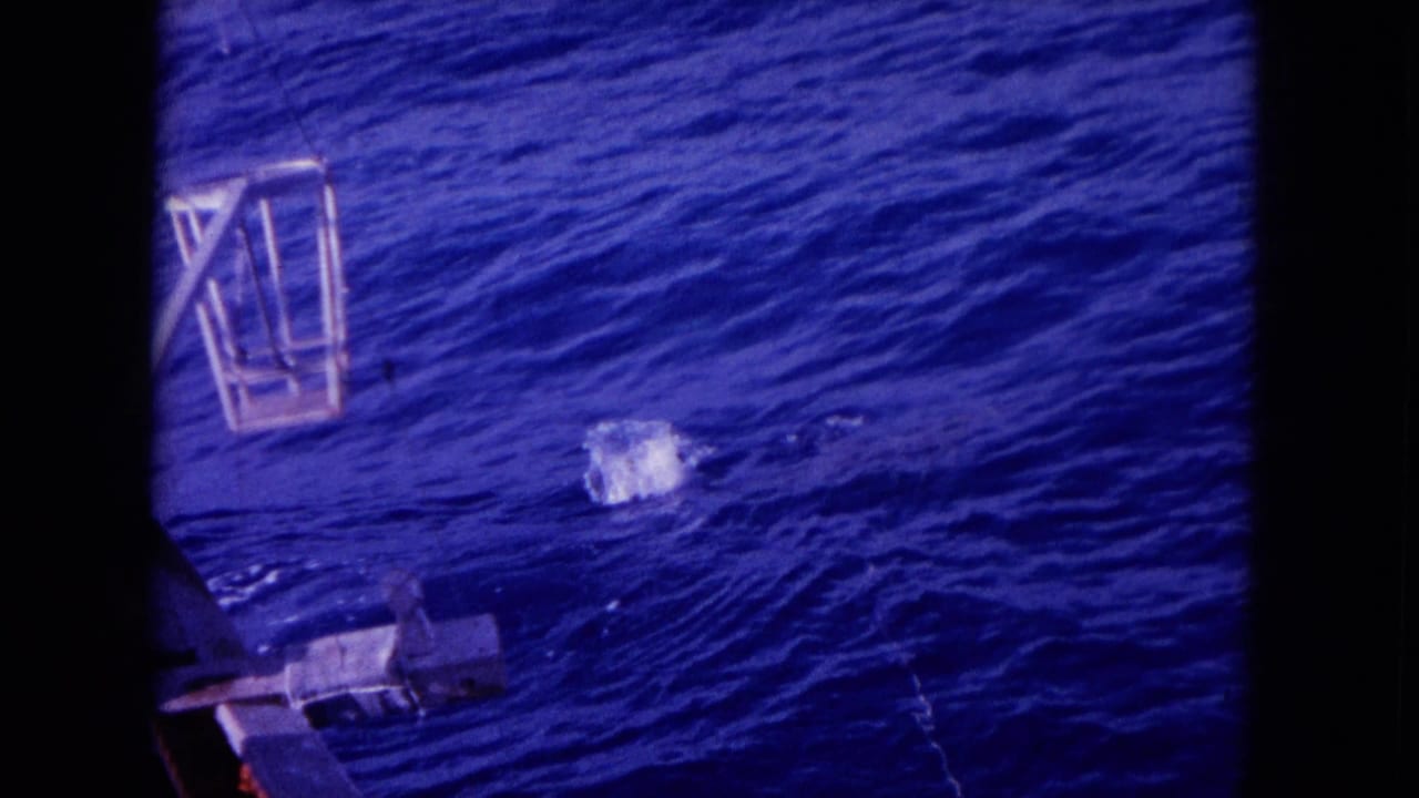 Blue ocean surface with fishing gear or boat hardware at the left edge and dark 8mm frame borders.