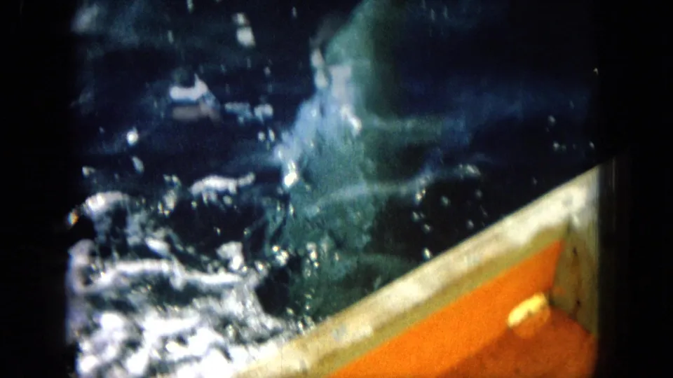 1964 Hawaii 8mm frame of churning ocean water against a boat side with orange deck trim and soft handheld focus.