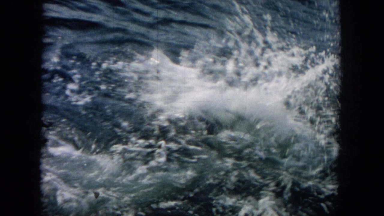 1964 Hawaii 8mm frame with a forceful white splash over dark water as the dolphin is mostly hidden.