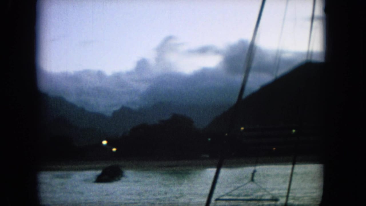 1964 Oahi, Hawaii harbor view with shadowed mountains, calm water, faint shoreline lights, and dark rigging or posts crossing the frame.
