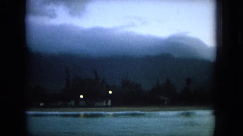 1964 Oahi, Hawaii harbor view with soft blue-gray exposure, distant mountains, silhouetted shoreline, and small lights near the water.