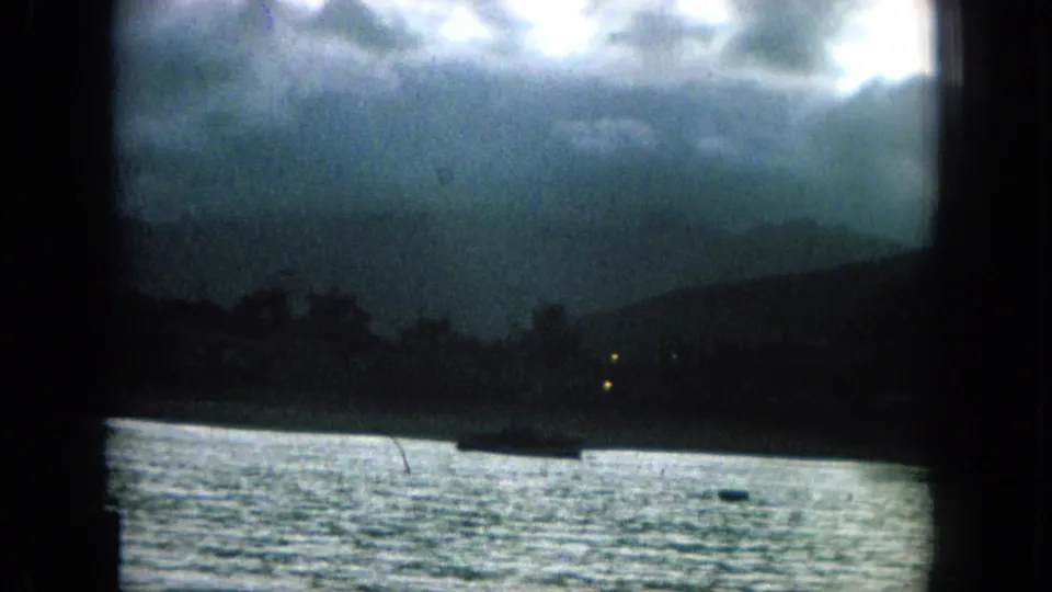 1964 Hawaii home-movie frame showing dark coastal water under a cloudy sky, viewed through heavy 8mm frame edges.