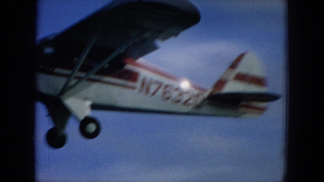 White red-striped single-engine airplane in flight against blue sky.