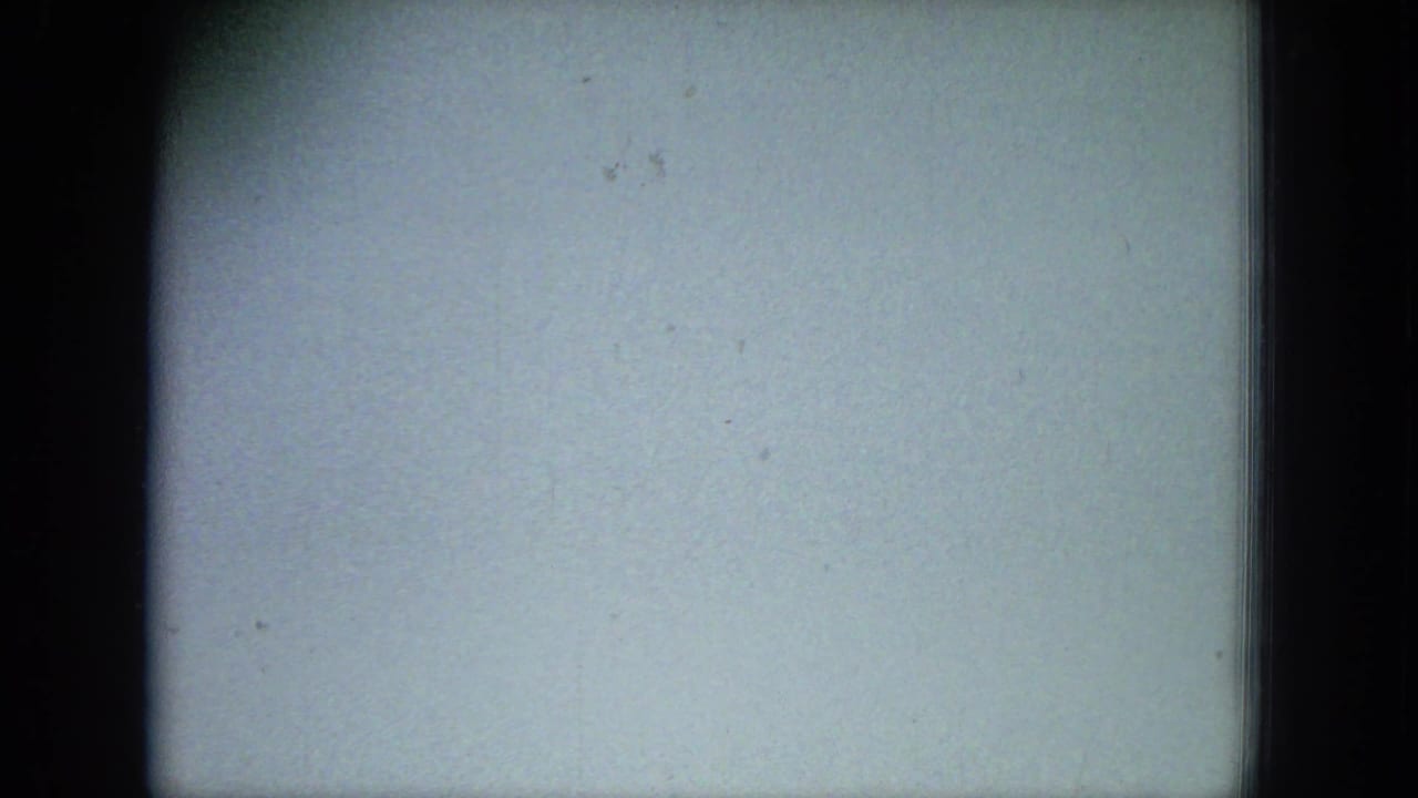 Mostly blank pale film frame with dark borders and small specks.
