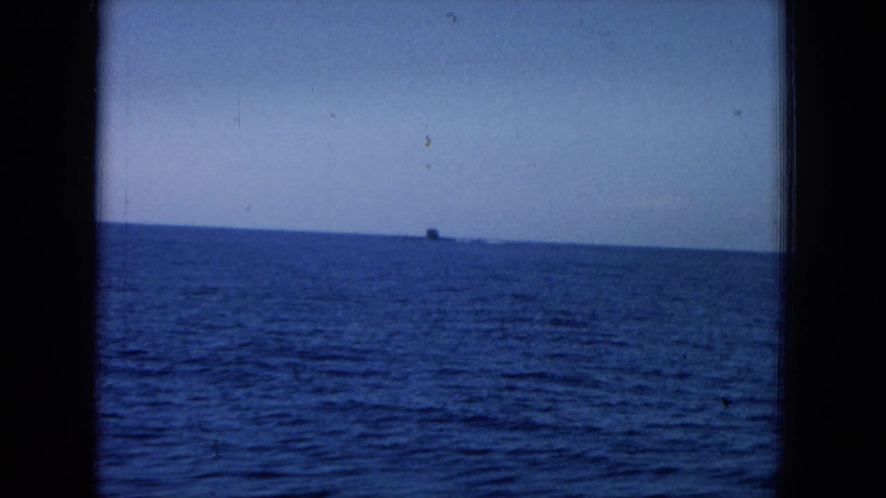 Open ocean and pale sky seen through a dark window frame, with a tiny distant object near the horizon.