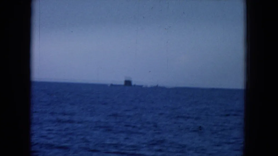 1964 8mm Hawaii home-movie frame showing blue ocean, pale sky, and a distant vessel-like silhouette near the horizon.