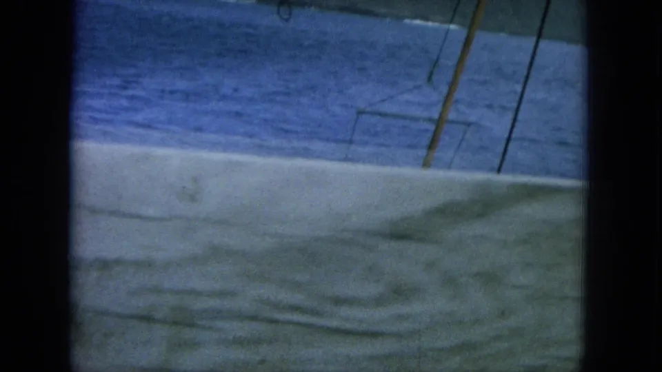 The 8mm frame catches a tilted ship deck view with blue sea, pale deck, and slender rigging or mast lines.