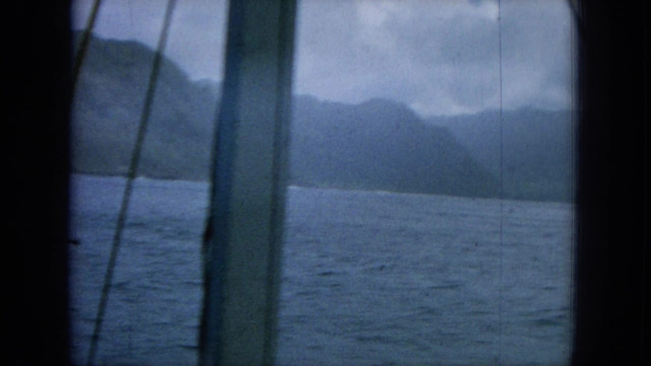 Ocean and mountain shoreline seen through dark boat framing and rigging.