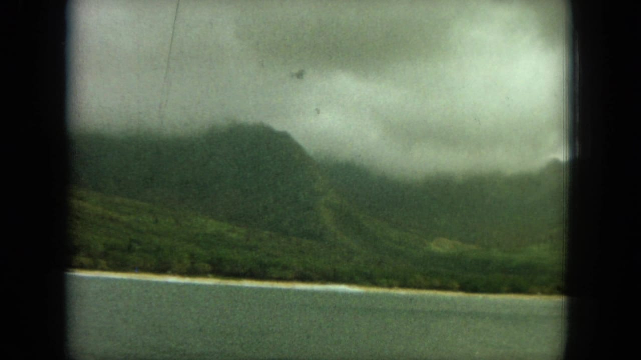 Cloud-covered coastal ridge with water and a thin shoreline in the foreground.