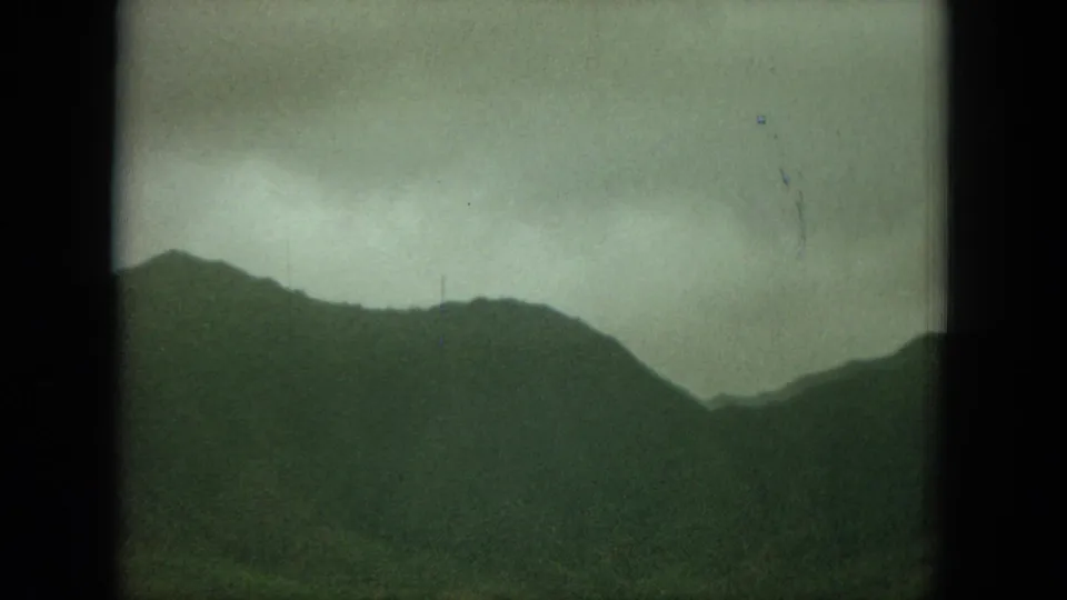 1964 Hawaii 8mm frame showing a silhouetted mountain ridge under a muted gray-green sky.