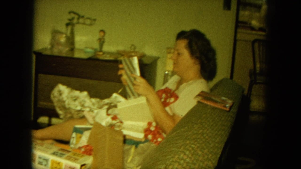 Woman examines a striped gift while sitting beside open boxes and wrapping paper.