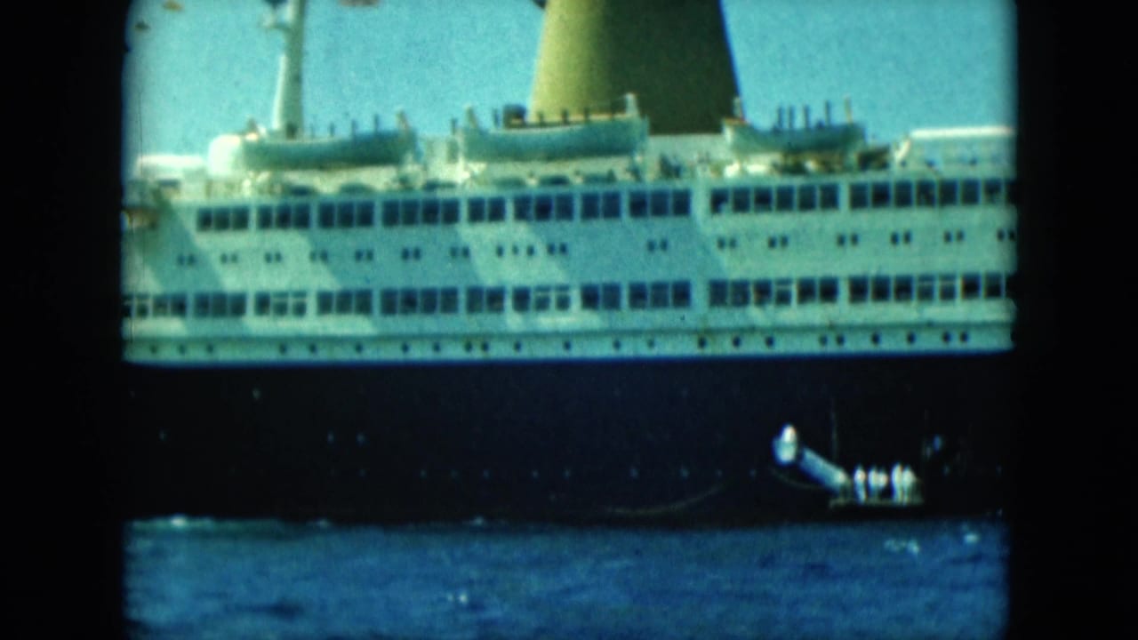 The ocean liner's side dominates the frame while a small boat with people aboard appears alongside on the water.