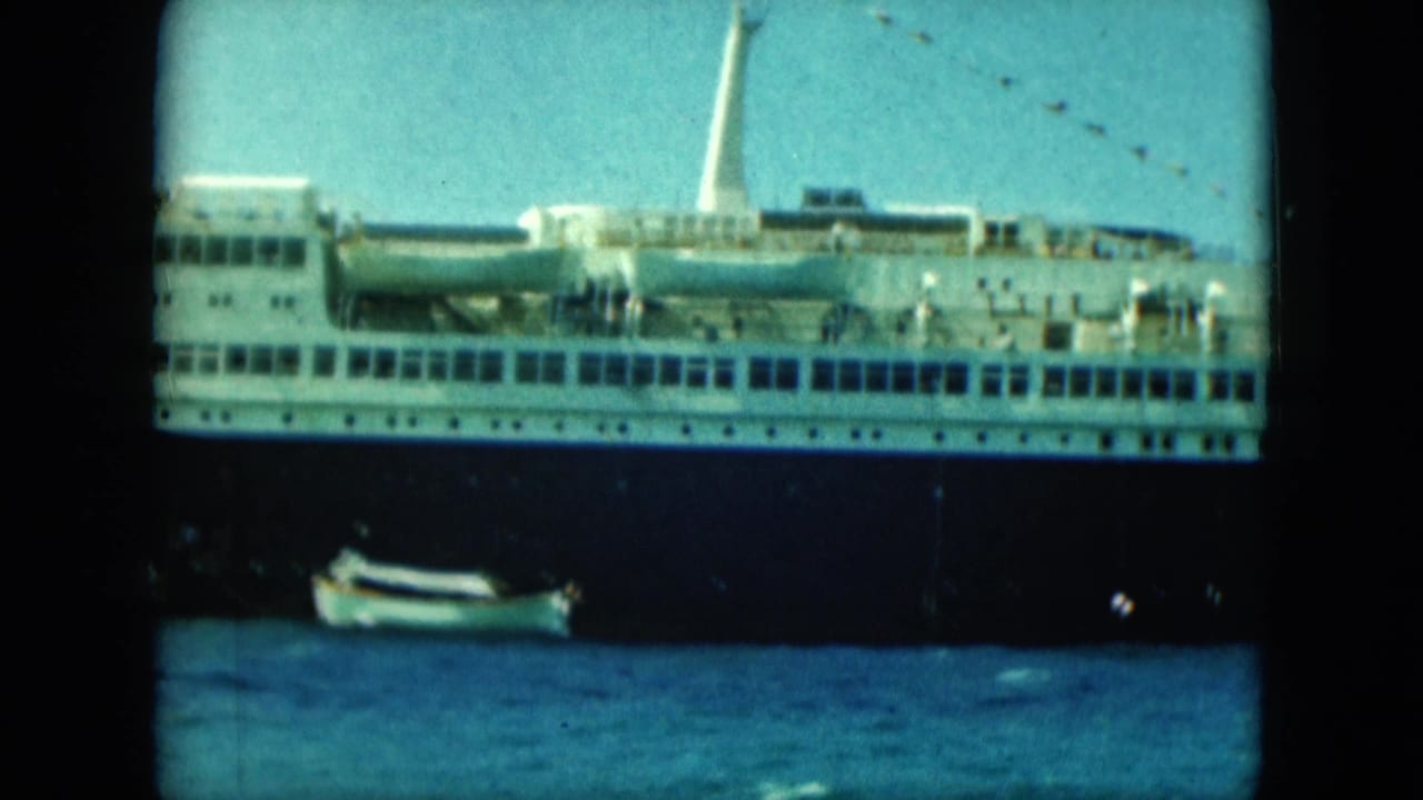 Ocean liner side view with lifeboats and a small boat on the water below.