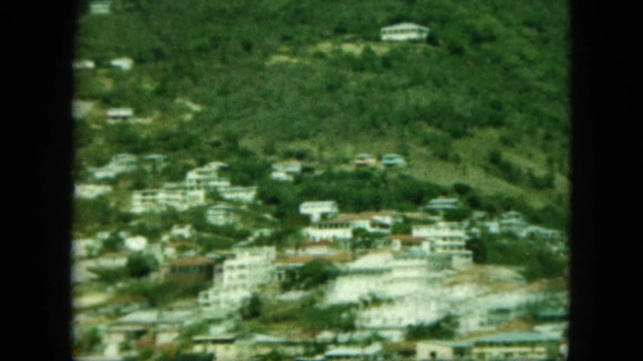Hillside houses and waterfront buildings with a dark vertical frame bar.