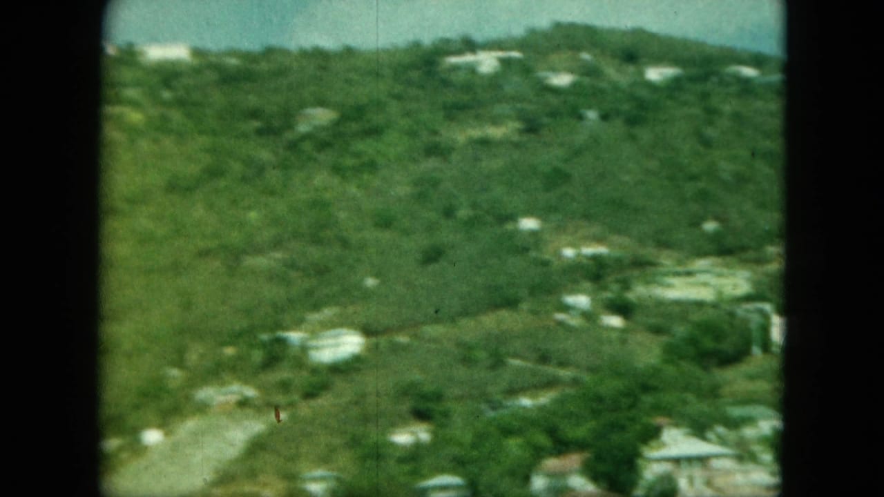 Soft 8mm view of green hills with scattered light buildings and a dark film border.