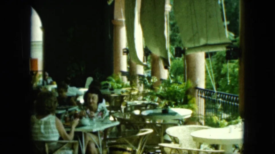 The final frame shows diners under a shaded arcade with wicker seating, potted plants, railings, and bright outdoor light.