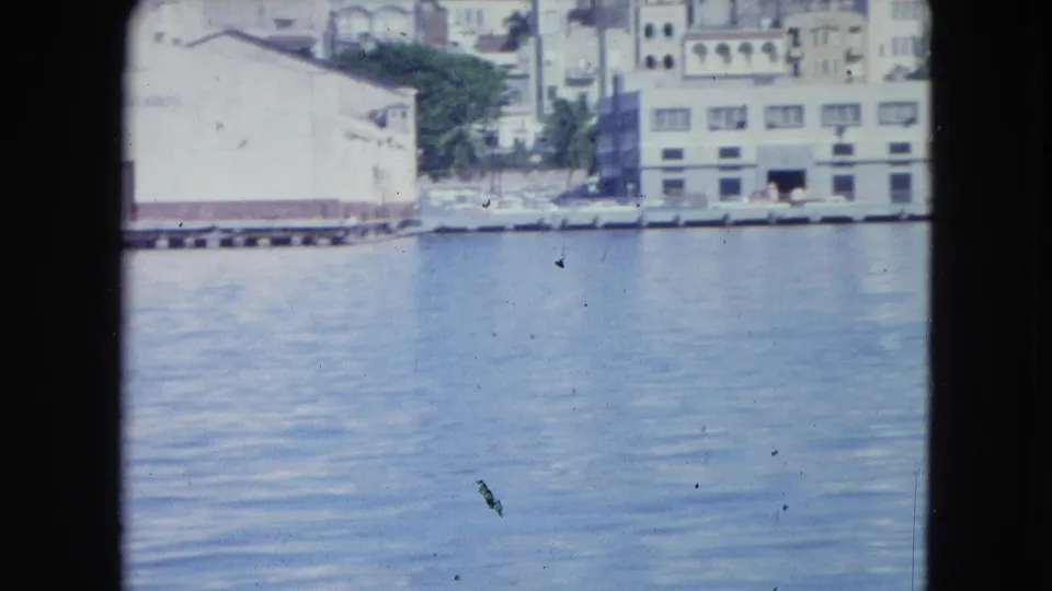 San Juan waterfront from the boat, with calm water, pale buildings, dock edge and urban facades in the background.