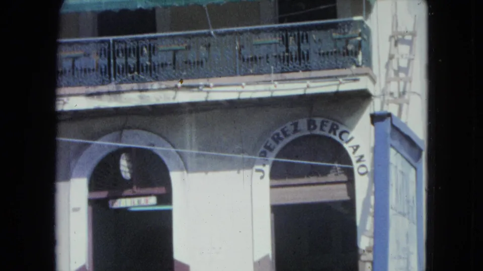 San Juan building facade with arched storefront entrance, balcony railing, awning, and visible business lettering.
