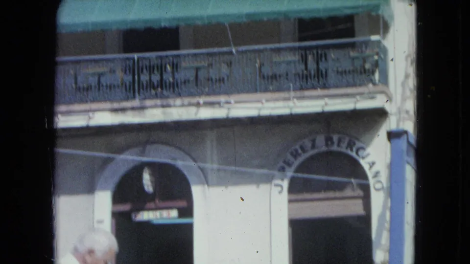 1964 San Juan storefront facade with balcony, awning, arched opening, and partially readable lettering.