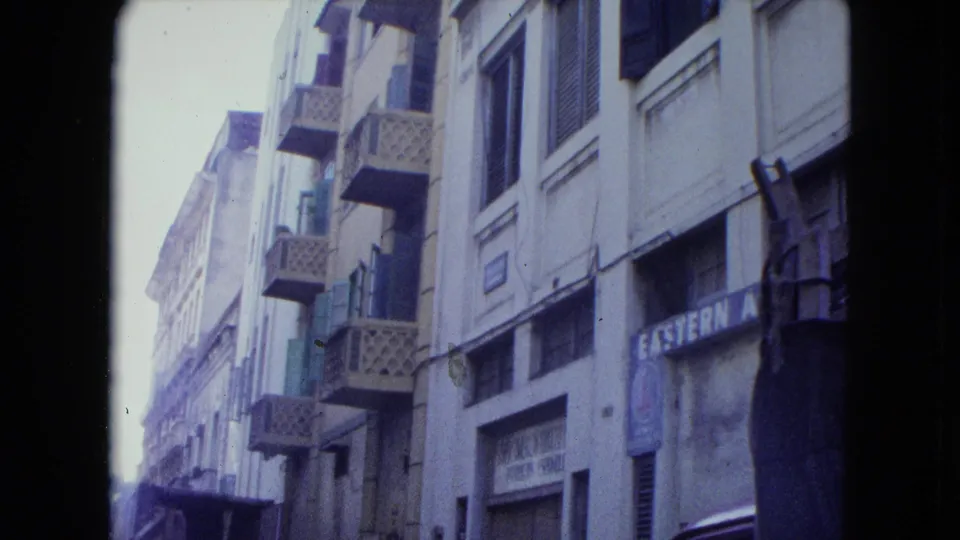 The camera tilts toward San Juan building facades, showing balconies, shuttered windows, and partially legible storefront signage.