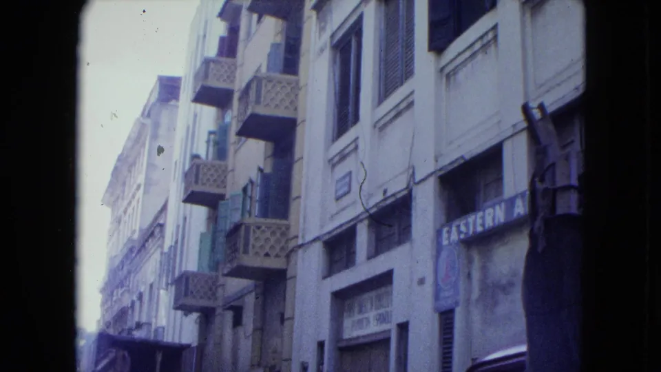 1964 San Juan street facade with older buildings, latticed balconies, and a partially readable faded storefront sign.