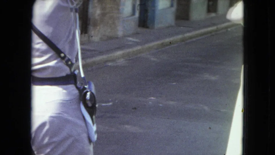 Cropped 1964 San Juan street frame showing the side and back of a light-uniformed man with radio equipment.