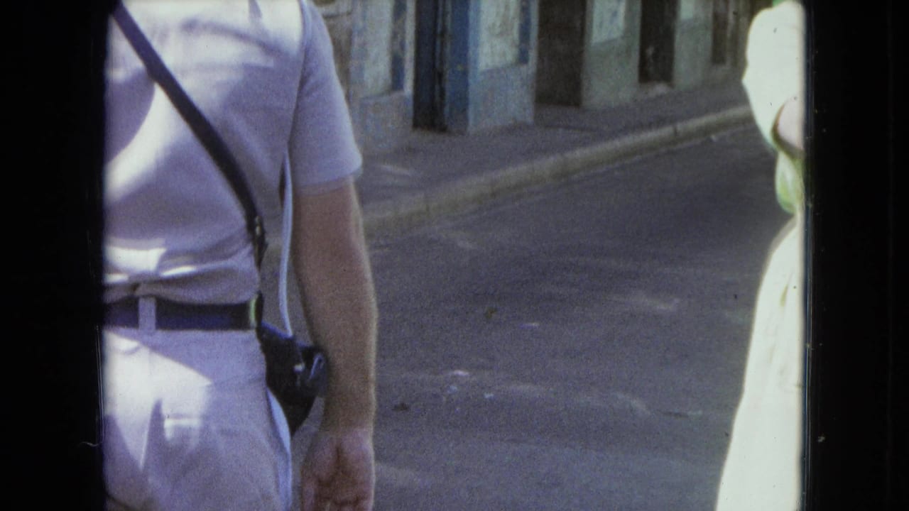Man with shoulder strap and woman partly cropped beside a street curb.