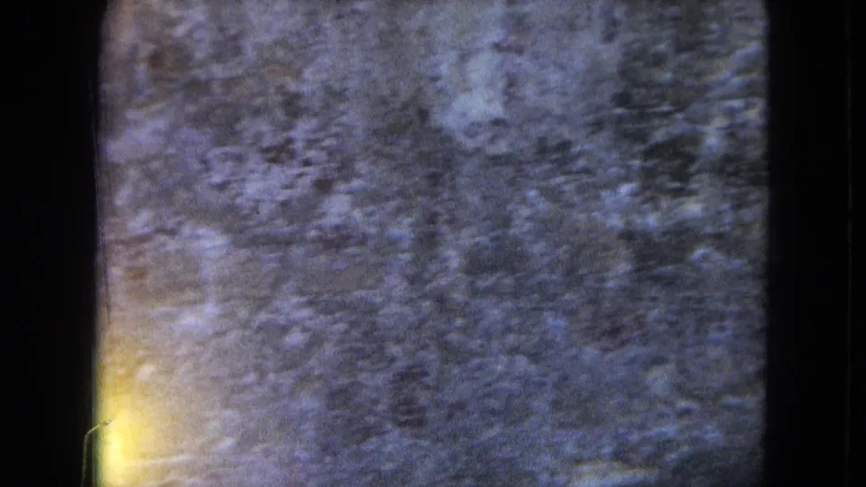 Close 8mm view of textured San Juan wall surface, with soft focus, grain, and dark gate edges visible.