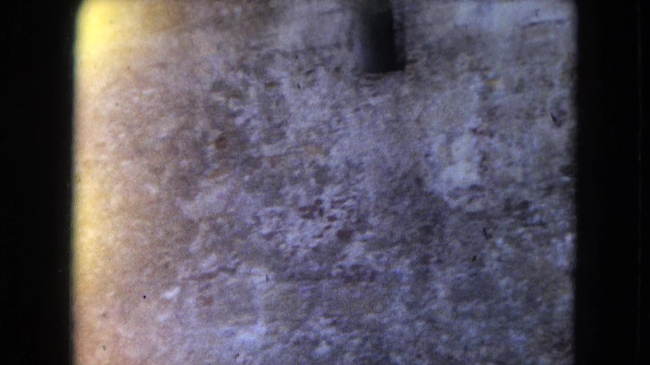 1964 8mm San Juan footage begins on a blurred close view of weathered stone or fortification surface with visible film edge and exposure variation.