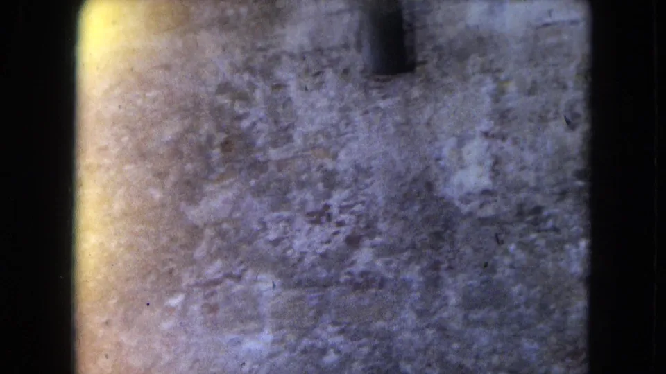 1964 8mm San Juan footage begins on a blurred close view of weathered stone or fortification surface with visible film edge and exposure variation.
