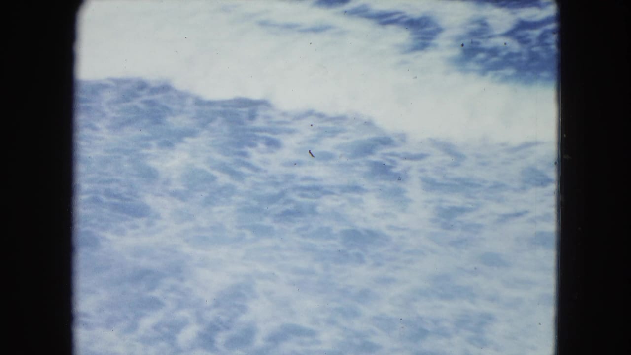 Foamy blue surf appears darker near the top with film dust and gate edges.